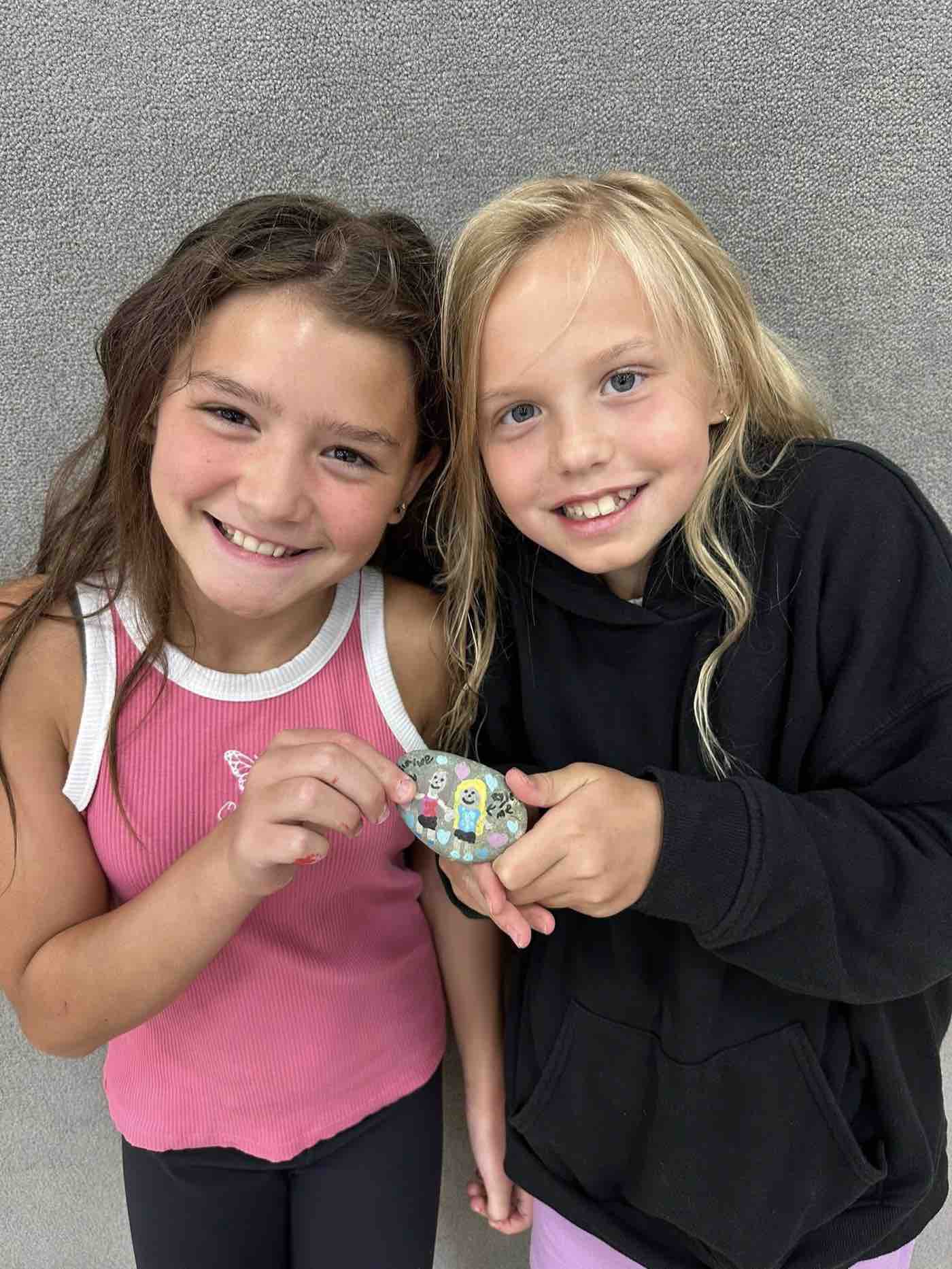 Isla and Rylee holding a painted rock together and laughing