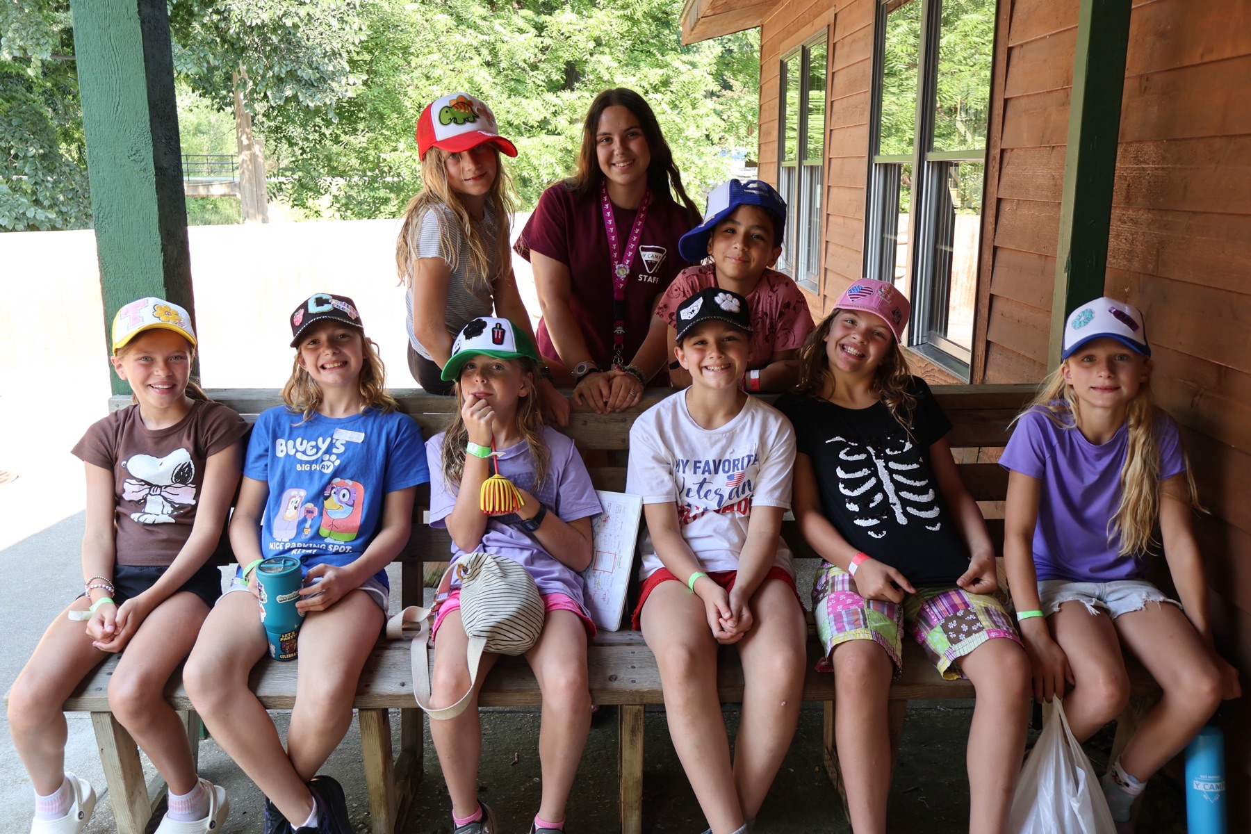 A cabin group smiling together in the decorated hats they made at camp