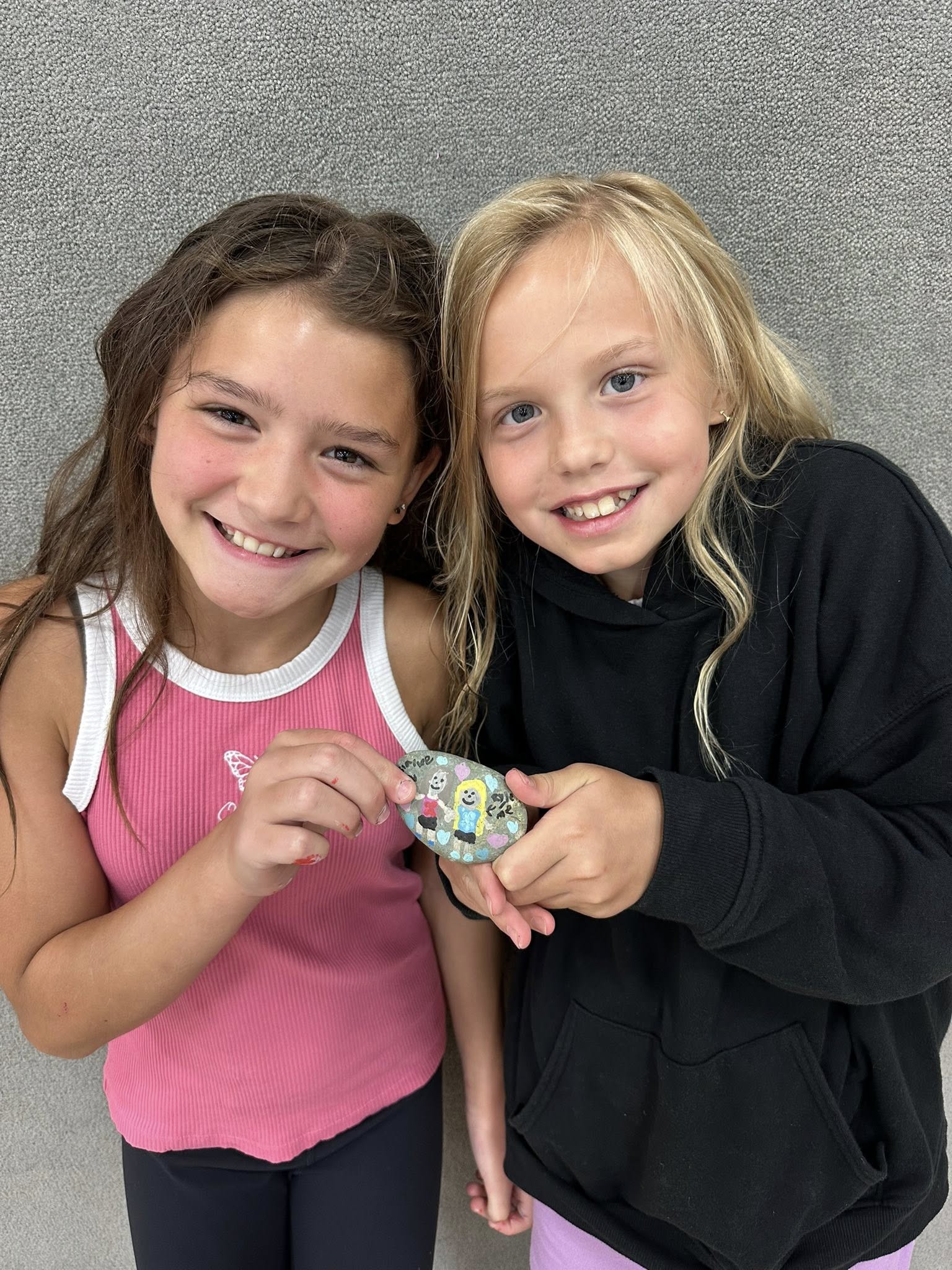 Isla and Rylee holding a painted rock together and laughing